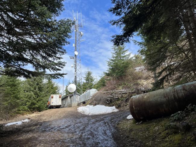 gravel road ending at the top of the hill with trailers and radio tower