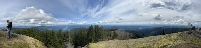 Panorama of view from summit with man standing at left