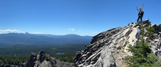 Summit Me standing on summit with view of mountains in background